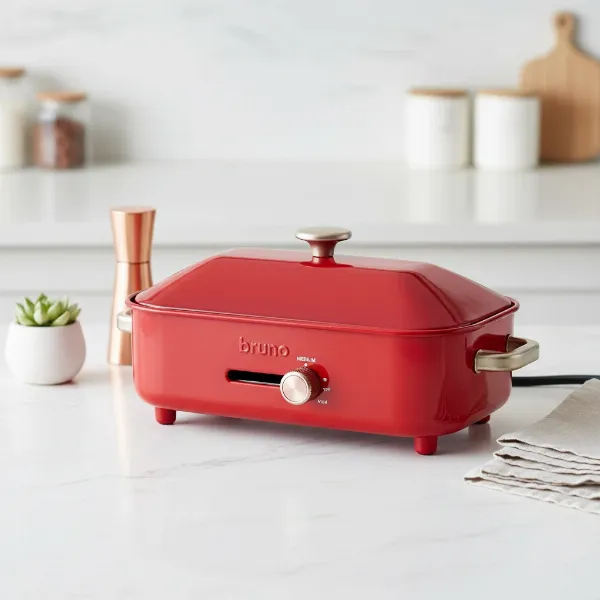 A vibrant red Bruno Compact Hot Plate, retro design, on a modern kitchen counter.