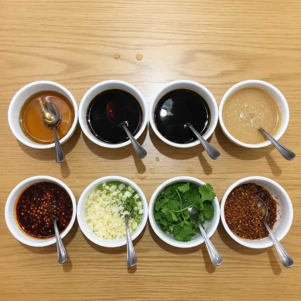 Various hot pot dipping sauce ingredients displayed in small bowls, ready for customization