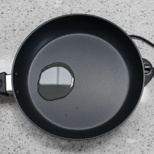 Water pooling in a warped electric skillet, demonstrating uneven surface.